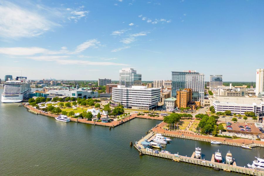 Attain Downtown apartment homes with Aerial view of a waterfront city with boats docked, modern buildings, and clear blue sky.