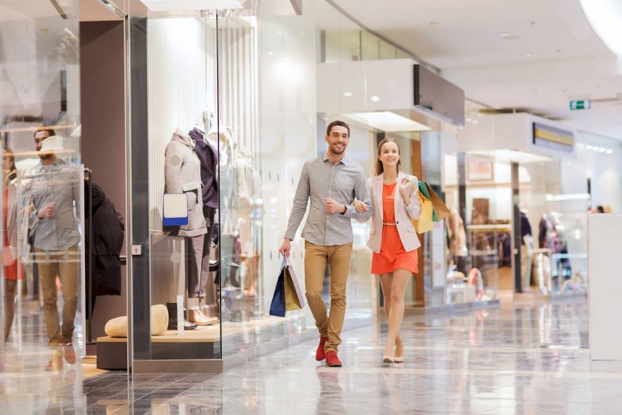 Attain Downtown apartment homes with A smiling couple walks arm in arm through a shopping mall, carrying several shopping bags.