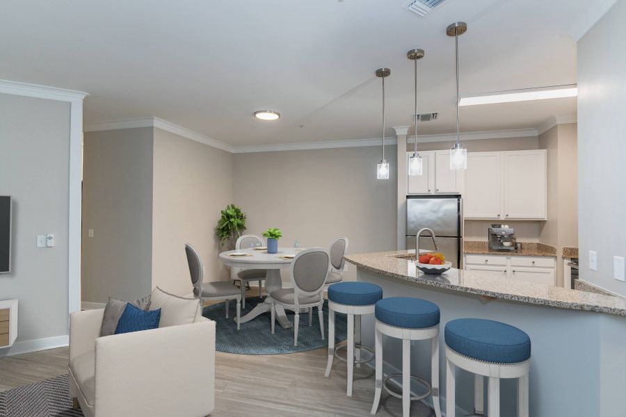 Attain Downtown East apartment homes with Modern kitchen and dining area with white cabinets, round table, blue stools, and pendant lights.