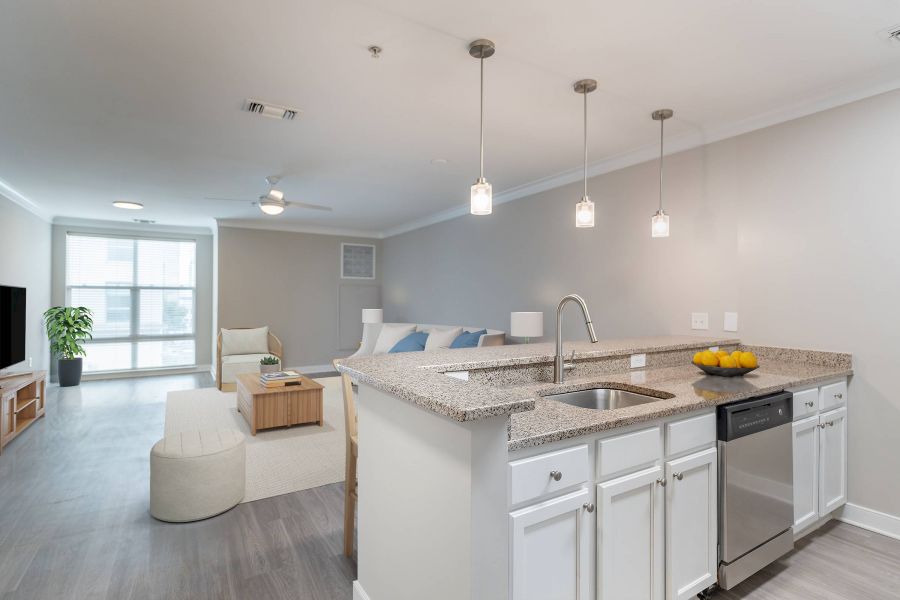 Attain Downtown East apartment homes with Modern open-plan living room and kitchen with pendant lights, a sofa, and a countertop with a bowl of lemons.