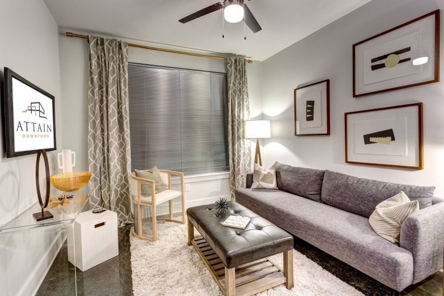 Attain Downtown apartment homes with Modern living room with a gray sofa, art on the walls, and a TV displaying "Attain Downtown.