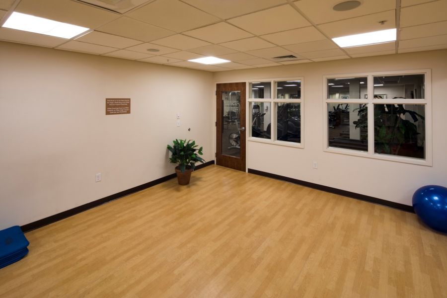 Attain Downtown East apartment homes with Empty exercise room with wood flooring, a plant, blue exercise mats, and a blue exercise ball in the corner.
